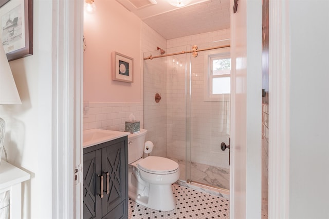 bathroom featuring a wainscoted wall, toilet, tile walls, a shower stall, and vanity