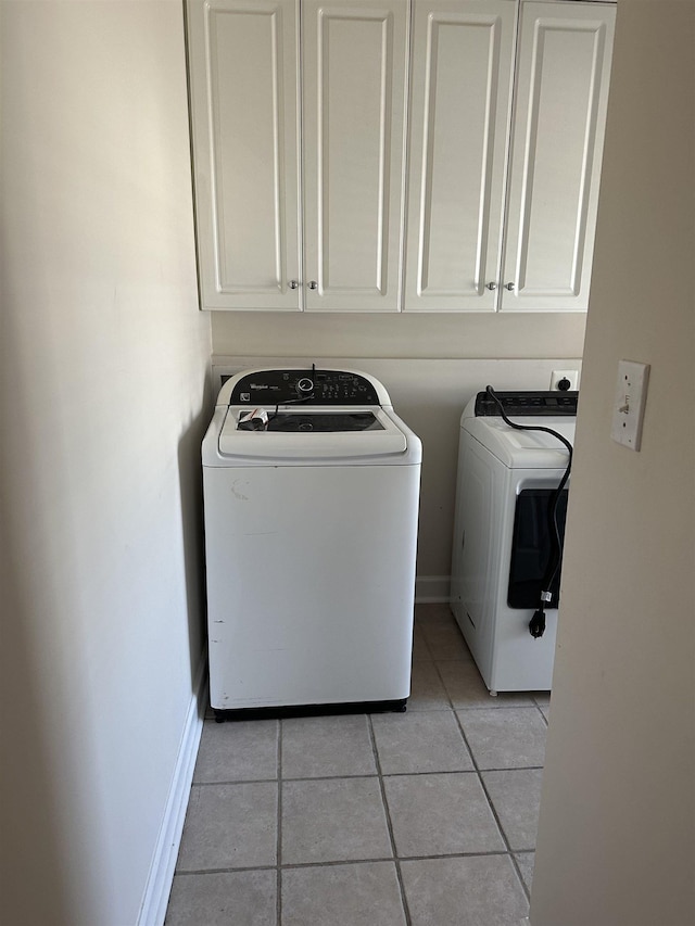 laundry room featuring cabinets, light tile patterned floors, and washer and dryer