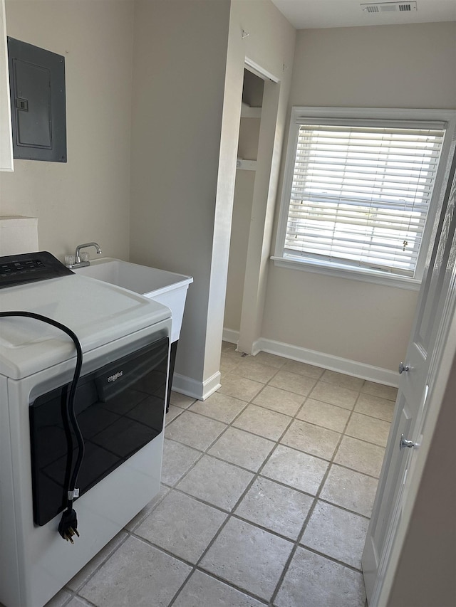 washroom with electric panel, sink, light tile patterned flooring, and washer / dryer