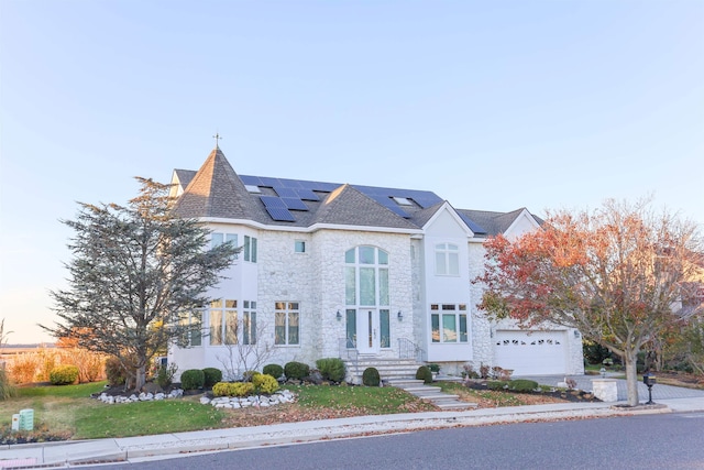 view of front facade with a garage and solar panels