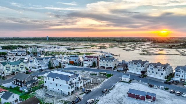 aerial view at dusk featuring a water view