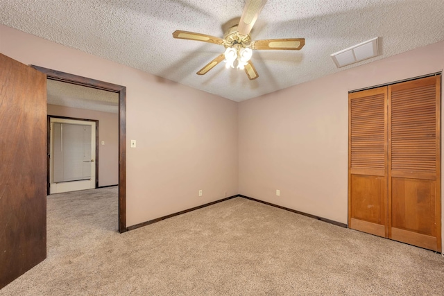 unfurnished bedroom featuring ceiling fan, a closet, light carpet, and a textured ceiling