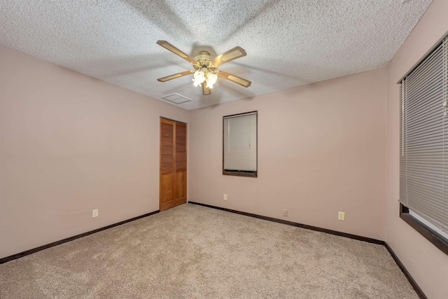 unfurnished bedroom with light carpet, a textured ceiling, and ceiling fan