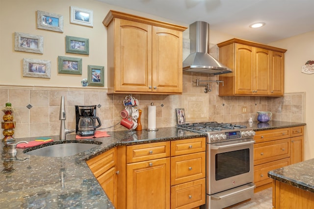 kitchen featuring stainless steel range, sink, wall chimney range hood, tasteful backsplash, and dark stone counters