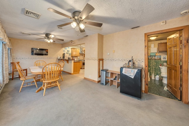 dining space featuring ceiling fan, light colored carpet, and a textured ceiling