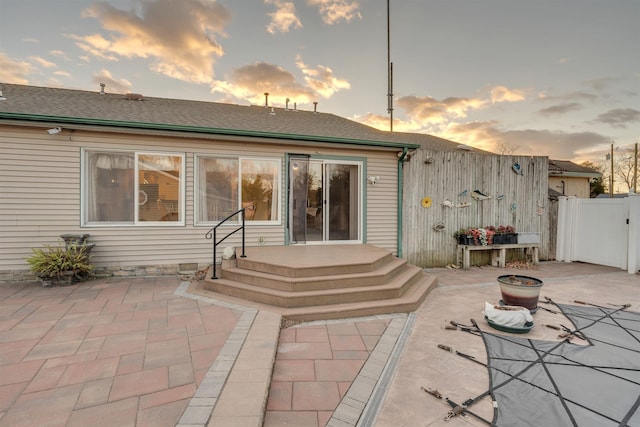 back house at dusk featuring a patio