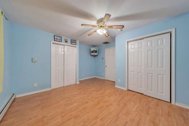 unfurnished bedroom with light hardwood / wood-style floors, baseboard heating, multiple closets, and ceiling fan