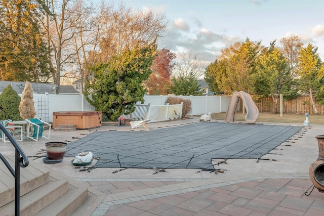 view of pool with a patio, a water slide, and a hot tub