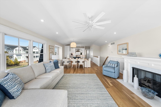 living room with ceiling fan, recessed lighting, wood finished floors, vaulted ceiling, and visible vents