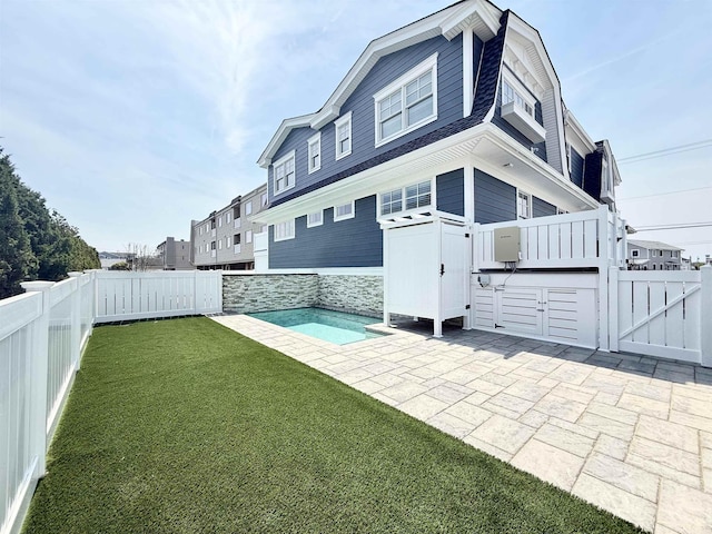 rear view of property featuring a patio, a fenced backyard, a yard, and a gambrel roof