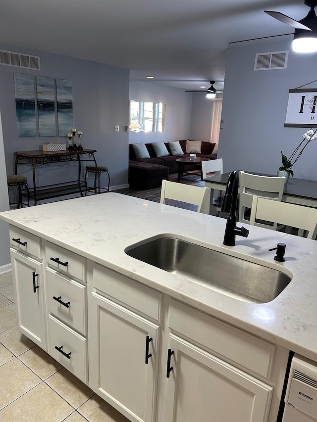 kitchen featuring light stone countertops, sink, light tile patterned flooring, and ceiling fan