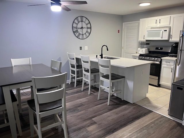 kitchen featuring white cabinets, stainless steel appliances, a breakfast bar area, and sink