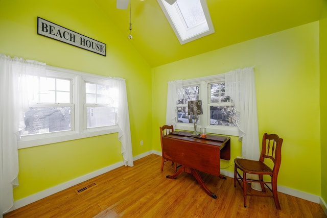 office area with ceiling fan, lofted ceiling with skylight, and hardwood / wood-style flooring