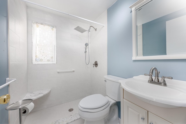 bathroom featuring a tile shower, vanity, and toilet