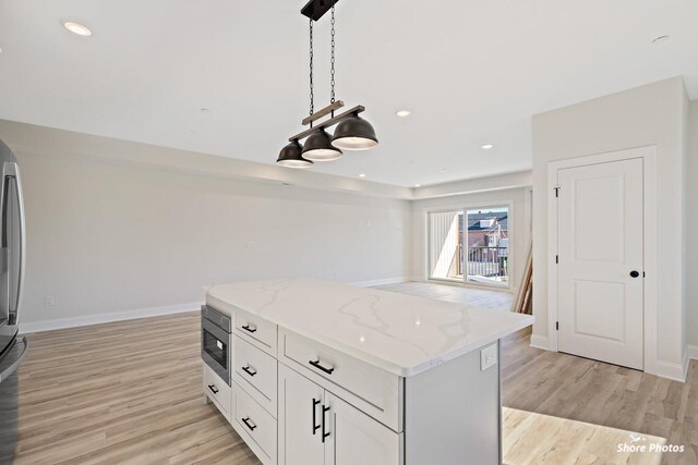3130 Pacific Ave Unit 3130, Wildwood, NJ 08260 - kitchen with light wood-style flooring, stainless steel microwave, light stone counters, hanging light fixtures, and recessed lighting