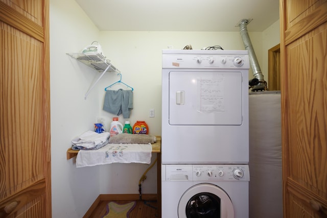 washroom featuring stacked washer / drying machine, baseboards, and laundry area