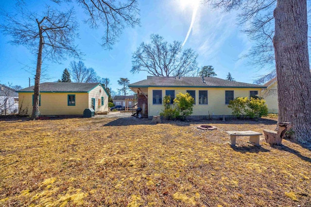 rear view of house featuring a lawn and an outdoor fire pit