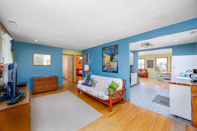 living area with recessed lighting, visible vents, and light wood finished floors