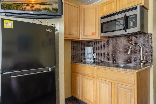 kitchen featuring decorative backsplash, light brown cabinets, refrigerator, and sink