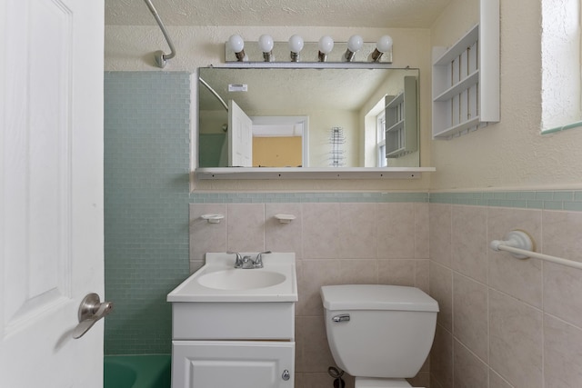 full bathroom featuring  shower combination, a textured ceiling, toilet, vanity, and tile walls