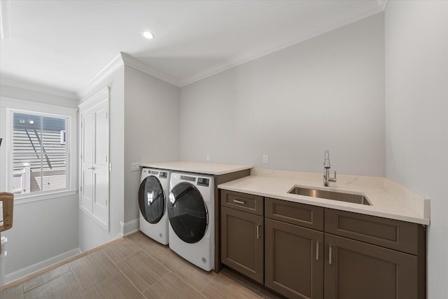 laundry area featuring separate washer and dryer, a sink, baseboards, ornamental molding, and cabinet space