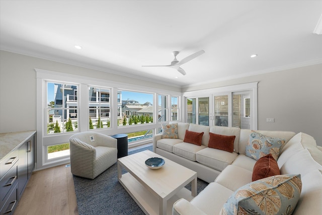 living area featuring a healthy amount of sunlight, crown molding, and light wood-style flooring