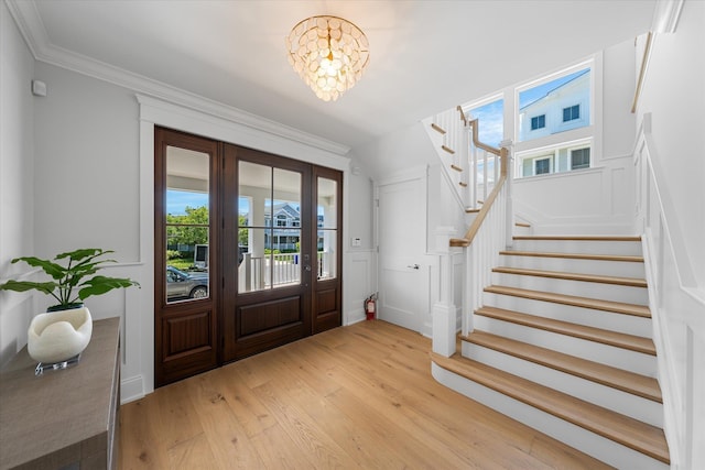 entryway featuring light wood-style floors, stairway, a chandelier, and crown molding