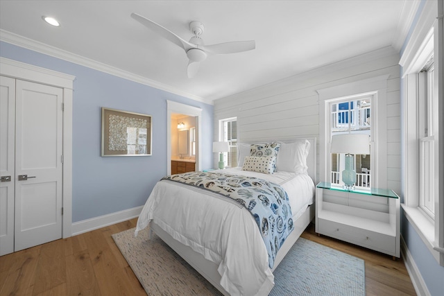 bedroom with ensuite bath, baseboards, ornamental molding, and wood finished floors