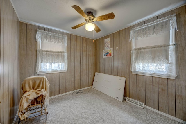 unfurnished room featuring wood walls, ceiling fan, and carpet flooring