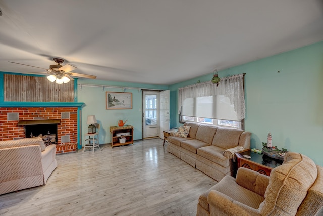 living room featuring ceiling fan, a fireplace, and light hardwood / wood-style flooring