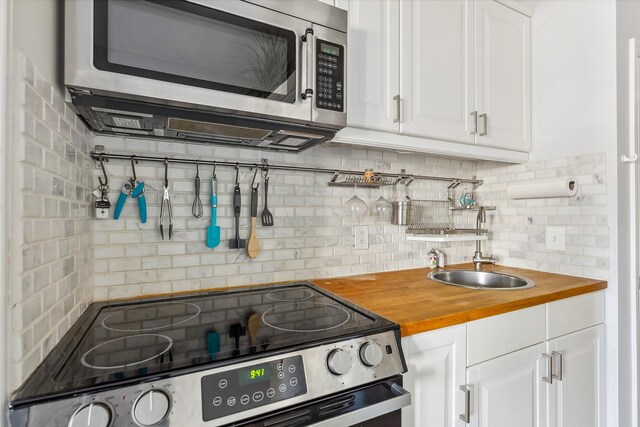 kitchen featuring tasteful backsplash, butcher block countertops, white cabinets, and appliances with stainless steel finishes