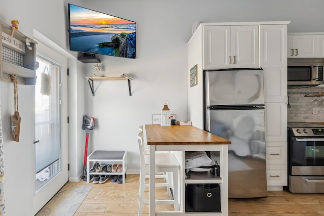 kitchen featuring baseboards, light wood-style floors, appliances with stainless steel finishes, white cabinetry, and tasteful backsplash