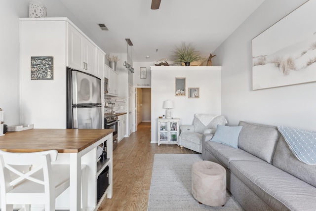 living area with ceiling fan, visible vents, and light wood-style flooring