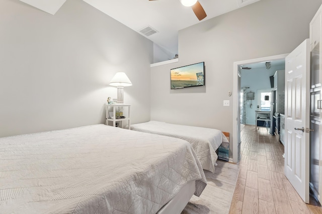 bedroom featuring lofted ceiling, light wood-style flooring, a ceiling fan, and visible vents