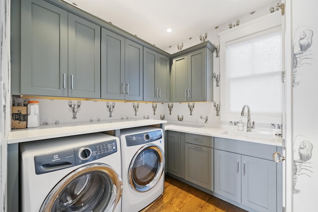 clothes washing area featuring sink, cabinets, independent washer and dryer, and light wood-type flooring