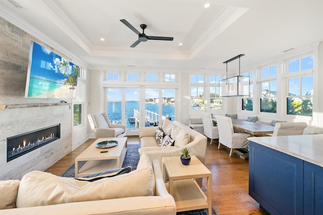 sunroom featuring ceiling fan, a tile fireplace, and a tray ceiling