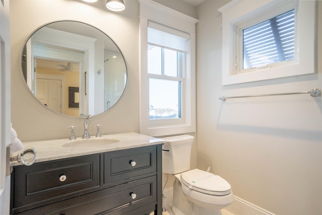 bathroom with vanity, toilet, ceiling fan, and a healthy amount of sunlight