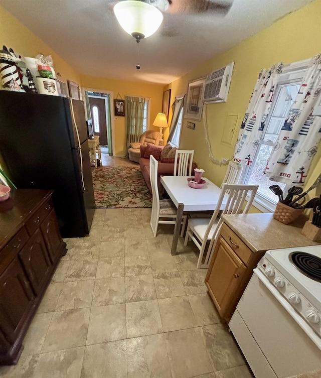 kitchen with light countertops, freestanding refrigerator, open floor plan, electric range, and an AC wall unit
