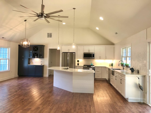 kitchen with appliances with stainless steel finishes, visible vents, high vaulted ceiling, and a sink