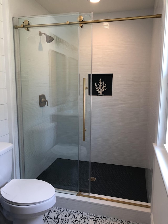 bathroom with a shower stall, toilet, and tile patterned flooring