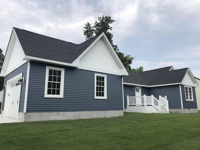 back of property featuring a yard, a shingled roof, board and batten siding, and a garage