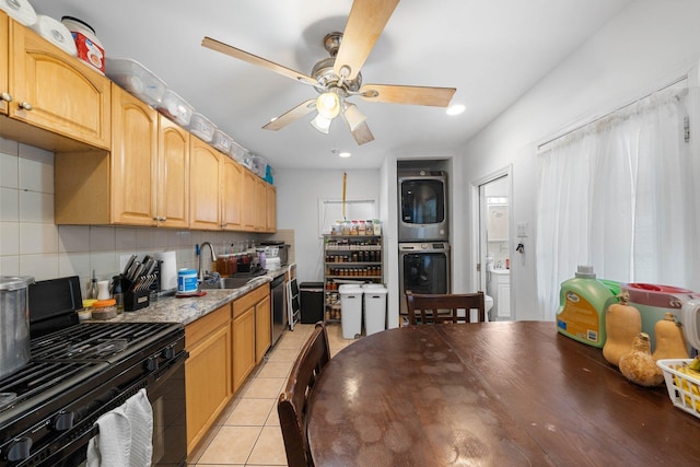 kitchen featuring appliances with stainless steel finishes, tasteful backsplash, sink, light tile patterned floors, and stacked washer and dryer