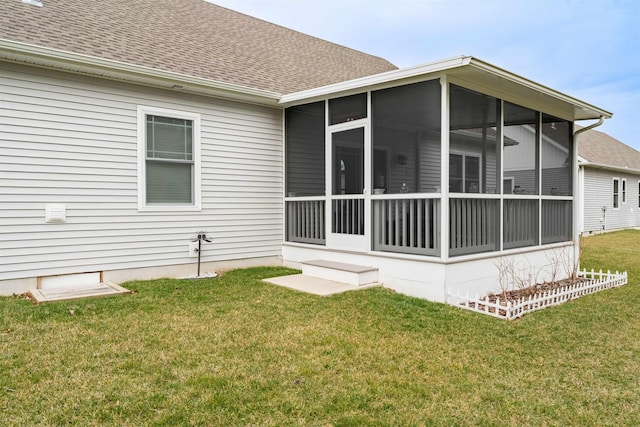 back of property with a sunroom, a yard, and roof with shingles