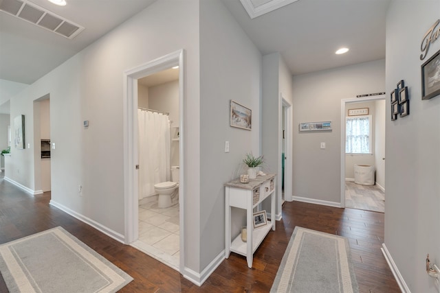 corridor with dark wood-type flooring, recessed lighting, baseboards, and visible vents