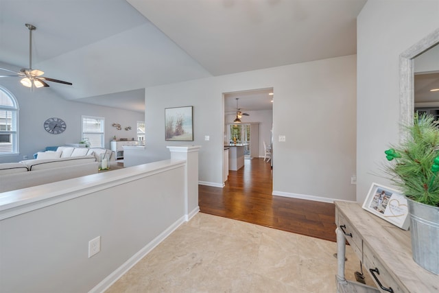 hall featuring lofted ceiling, wood finished floors, and baseboards