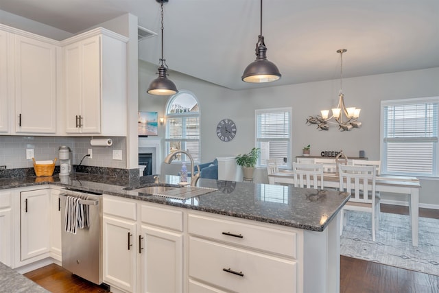 kitchen with dark wood-style floors, a peninsula, a sink, a notable chandelier, and tasteful backsplash