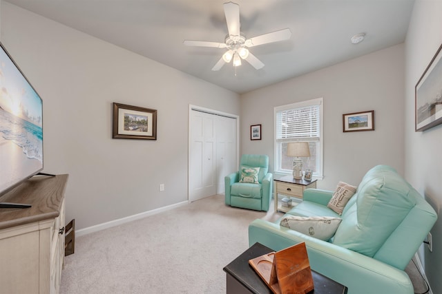 living area featuring baseboards, carpet, and a ceiling fan