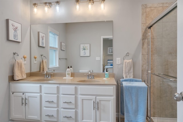 bathroom with a sink, tiled shower, and double vanity