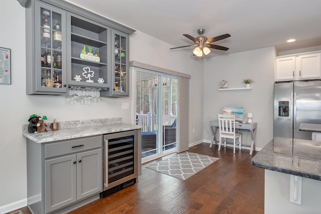 interior space featuring dark wood-type flooring, ceiling fan, indoor bar, beverage cooler, and stainless steel fridge with ice dispenser