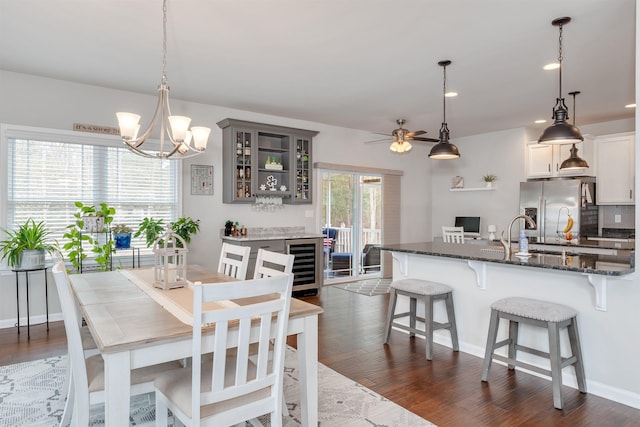 dining area featuring beverage cooler, ceiling fan with notable chandelier, dark wood finished floors, recessed lighting, and baseboards